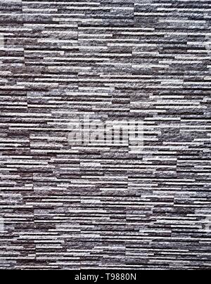 Picturesque, colorful and elegant facing of the wall of the fence, made of bonded thin plates of artificial granite, marble or other stone-forming mat Stock Photo