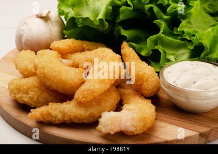 Delicatessen shrimp in breaded closeup with salad, garlic and sauce on the table Stock Photo
