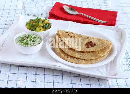 Chapati or Indian flat bread, which is a traditional and popular vegetarian breakfast or lunch item, with potato and onion curry and coconut chutney. Stock Photo