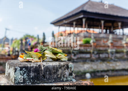 Traditional Balinese offerings canang sari near Bale Kembang (Floating pavilion) at Taman Gili Kertha Gosa, Semarapura, Klungkung, Bali, Indonesia Stock Photo