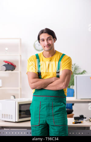 Young repairman repairing microwave in service centre Stock Photo
