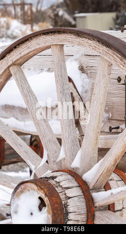 Clear Vertical Close up of the wheel of an old wooden cart against a snowy landscape in winter Stock Photo