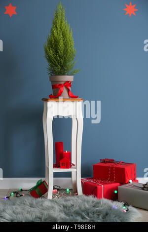 Thuya tree with Christmas gifts near color wall Stock Photo Alamy