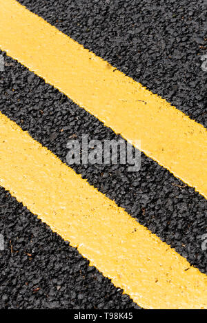 Freshly painted double yellow lines on new black tarmac road surface. No parking warning lines on fresh asphalt. Lined highway Stock Photo