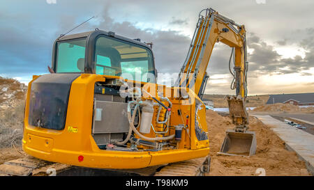 Construction site with an excavator against a dramatic sky filled with clouds Stock Photo