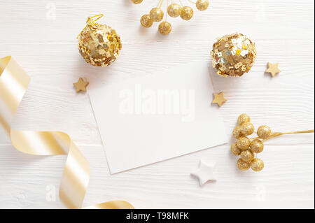 Christmas background for greeting card with place for text. x-mas golden toys and beige ribbon on wooden background. Flat lay, top view photo mockup Stock Photo