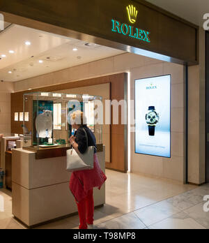 A woman passenger looks at a watch in a display in the Rolex retail