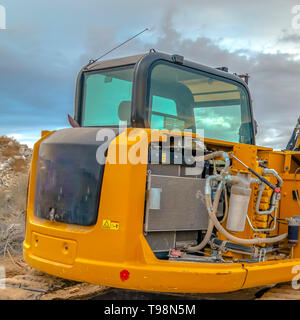Square Construction site with an excavator against a dramatic sky filled with clouds Stock Photo