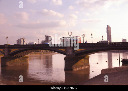 A red double-decker bus on Battersea Bridge crossing the River Thames, Chelsea Embankment, London, England, UK