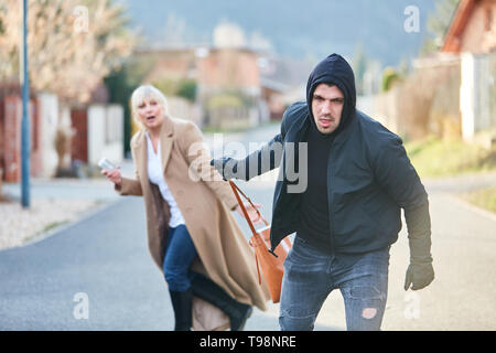 Thief on the run after stealing a handbag from woman in the street Stock Photo