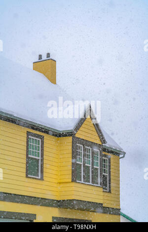Snowy yellow home viewed through falling snow Stock Photo