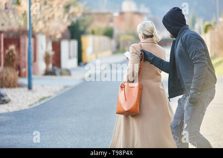 Thief stealing a handbag from an inattentive woman in the street Stock Photo