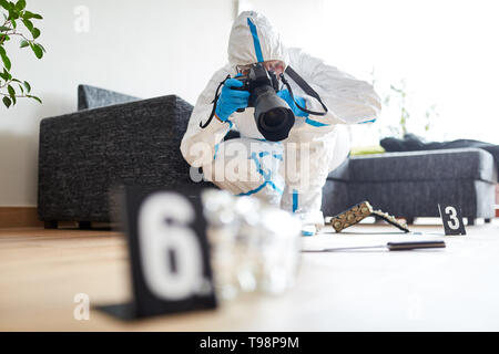 Forensic scientist with camera photographs evidence at the scene Stock Photo