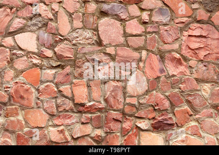 The wall is made of natural coarse red granite with embroidered borders of cement Stock Photo