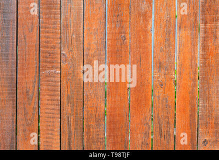 The aged old gray wooden fence is painted with orange paint, close-up Stock Photo