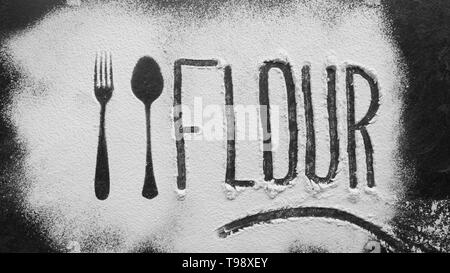 Flour word write on flour with spoon and fork silhouette made with flour on dark texture background. No gluten concept Stock Photo