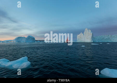 Icebergs and sailboat in Disko Bay on Midsummer, Greenland Stock Photo