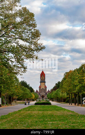 Walkway in beautiful park toward chapel complex, bell tower, funeral hall, and crematorium of Leipzig South Cemetery in Leipzig, Germany Stock Photo