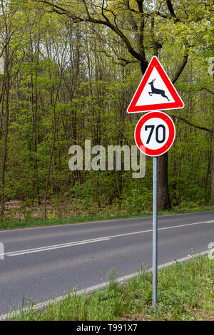 Wildlife crossing signs along a forested stretch of road Stock Photo