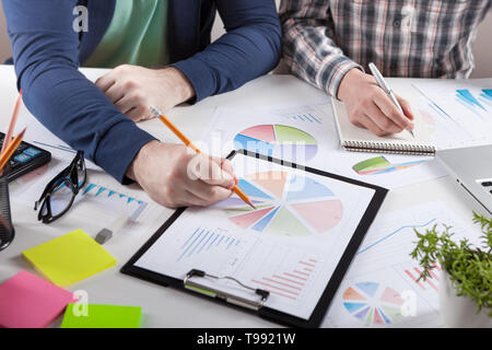 Business people discussing the charts and graphs showing the results of their successful teamwork.  Stock market chart and finger pointing on tablet i Stock Photo