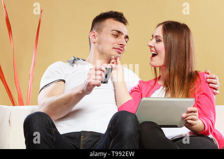Shopping consumerism leisure and people concept. Young couple with tablet pc and credit card on sofe at home doing shopping on internet Stock Photo