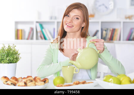 Beautiful young woman pouring tea in cup Stock Photo