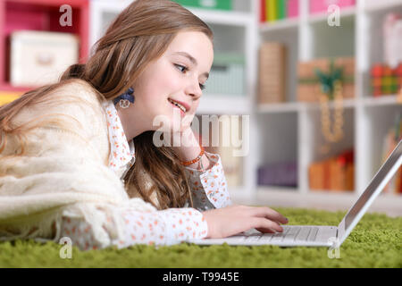 Emotional cute girl using laptop while lying on floor Stock Photo - Alamy
