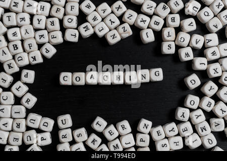 Word COACHING on wooden cubes on a black wooden table with copy space Stock Photo