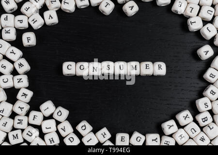 Word CONSUMER on wooden cubes on a black wooden table with copy space Stock Photo