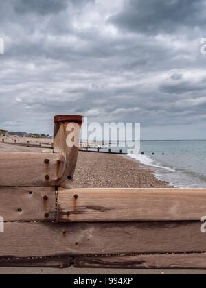 A worn and weathered wooden groyne on a pebble beach in the South of England Stock Photo