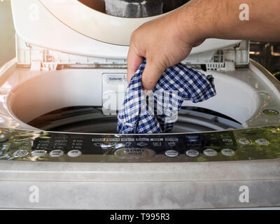 A man load dirty clothes in the washing machine. Stock Photo