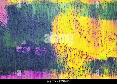 Old rusty surface painted with yellow, green, pink shabby paint, horizontal grunge background texture Stock Photo