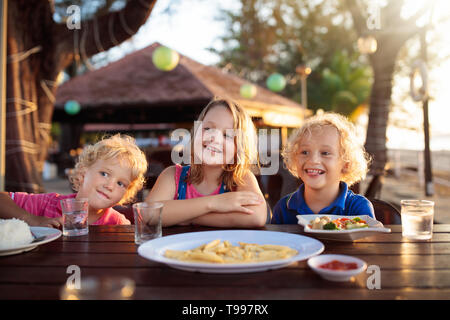 Family eating lunch on tropical beach. Kids in outdoor restaurant of exotic resort in Asia. Asian food for children. Little boy and girl eat dinner at
