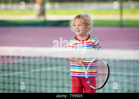 Child playing tennis on indoor court. Little boy with tennis racket and ball in sport club. Active exercise for kids. Summer activities for children.  Stock Photo