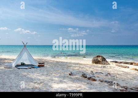 romantic white picnic tent on white sand beach with crystal clear water and blue sky at background