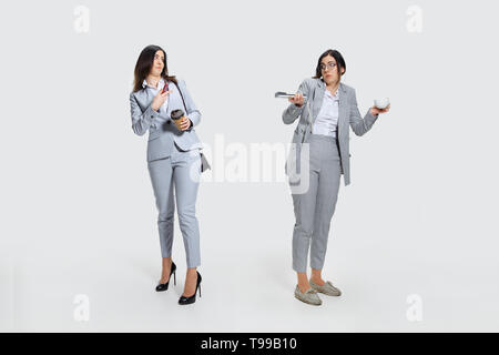 Look at yourself. Young woman comes to work rumpled and untidy because it's deadline. Colleague in suit laughs at her. Concept of office worker's troubles, business or problems with mental health. Stock Photo