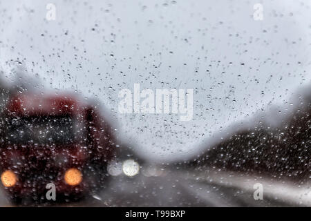 Photo through the windshield of the car in the raining evening, in the blur lights, track, trucks. Stock Photo