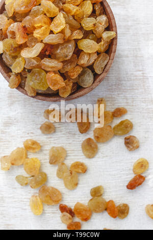 Light yellow raisins in a wooden bowl on a light white background. Close-up. Isolated Stock Photo