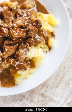 Braised beef, beef stroganoff with gravy on mashed potatoes. Close-up, top view Stock Photo