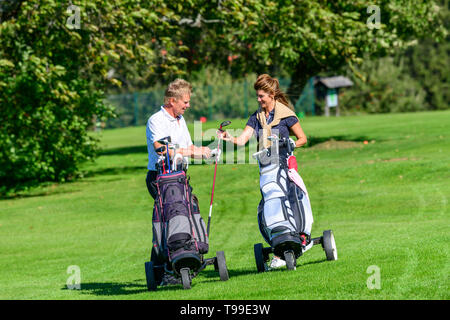 Two golfers on the way on fairway enjoying a golfgame Stock Photo