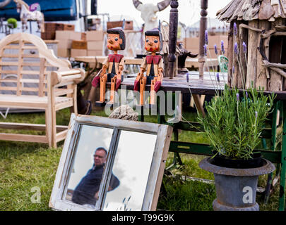 Antique stall with two wooden marionette style dolls sitting on table, mirror, with man's reflection in foreground, Ripley, North Yorkshire, England Stock Photo