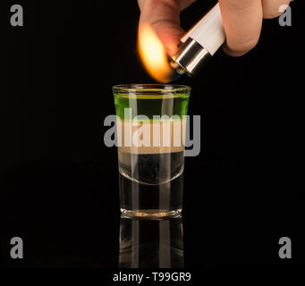 bartender sets fire to a mixed alcoholic cocktail in a shot glass, close-up Stock Photo