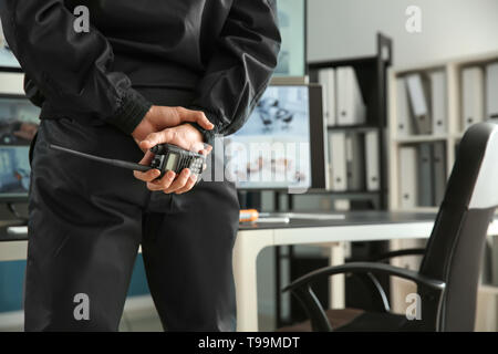 Security guard with portable radio transmitter monitoring modern CCTV cameras in surveillance room Stock Photo