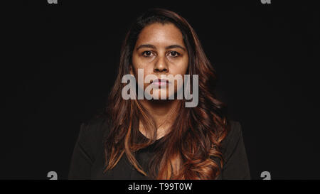 Close up of a businesswoman isolated on black background. Portrait of a woman in formal wear looking at camera. Stock Photo