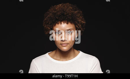 Portrait of a young woman isolated on black background. Woman with curly hair looking at camera. Stock Photo