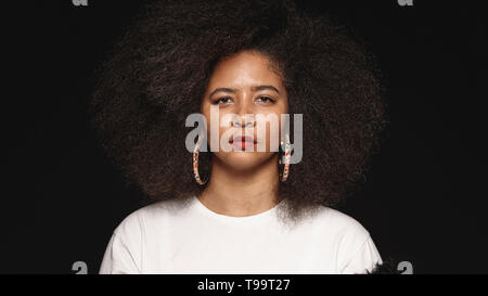 Woman in afro hairstyle isolated on black background. Close up of woman looking at camera. Stock Photo