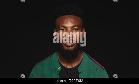 Portrait of african male looking at camera. African man with beard and spiky hair style isolated on black background.