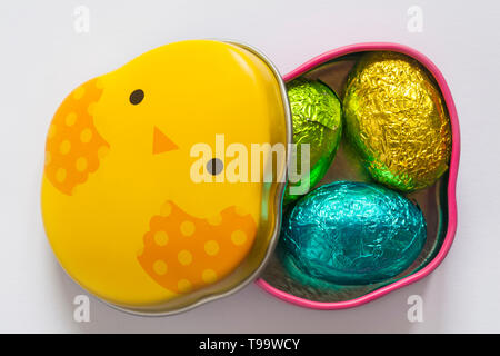 Easter Chick tin with lid removed showing three foil covered mini Easter eggs isolated on white background - 3 foiled solid milk chocolate mini eggs Stock Photo