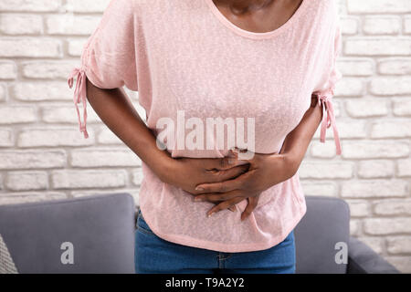 Young Woman Suffering From Stomachache At Home Stock Photo