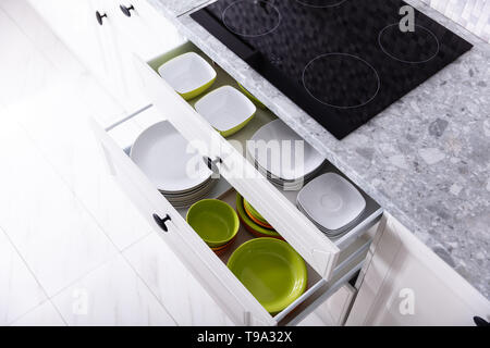 Set Of Different Clean Plates Inside The Opened Drawers In Kitchen Stock Photo